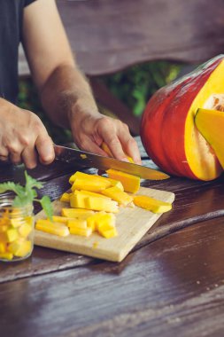 Yazlık evde olgunlaşmış balkabağını kesen erkek elleri.