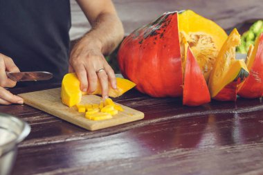 Yazlık evde olgunlaşmış balkabağını kesen erkek elleri.