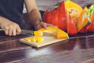 Yazlık evde olgunlaşmış balkabağını kesen erkek elleri.