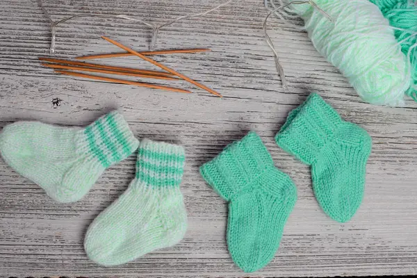 Yumuşak pamuktan yapılmış nane yeşili bebek çorapları, ahşap masadaki yeni doğan için mükemmel bir hediye.