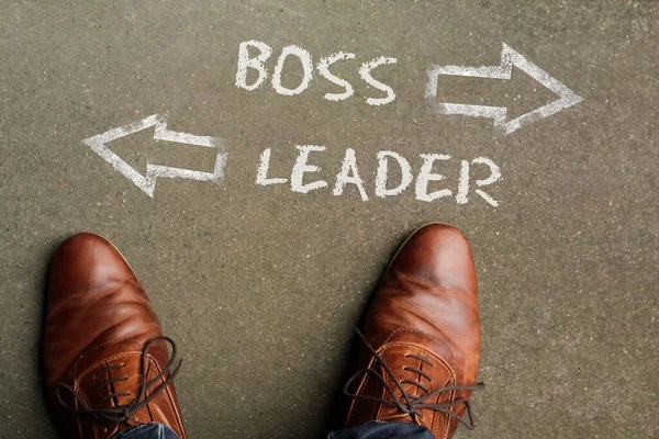 The words Boss and Leader written on the floor with two arrows pointing in opposite directions