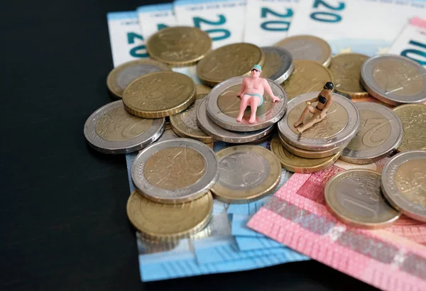 Bir yığın paranın üzerinde dinlenen ve bronzlaşan bir çiftin minyatür figürleri.