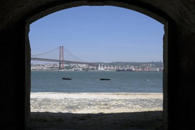 Portekiz, Lizbon 'da terk edilmiş bir binanın kapısından görünen ünlü asma köprü Ponte 25 de Abril.