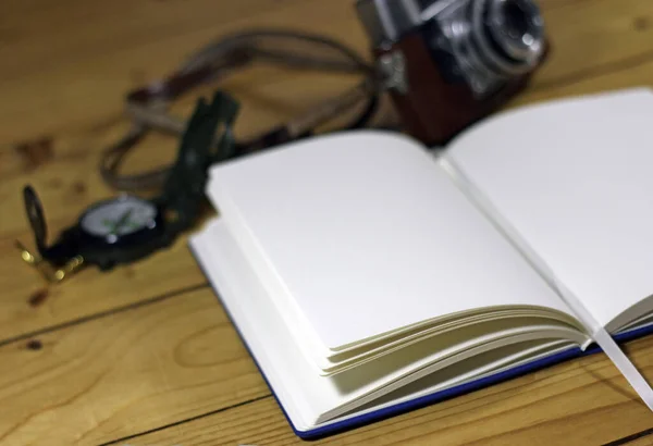 An empty travel journal with old-fashioned camera and compass