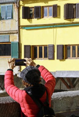 11 Kasım 2019 - Floransa, İtalya: Çinli turistler ünlü Ponte Vecchio 'nun akıllı telefonlarıyla fotoğraf çekmek için sıraya girdiler.