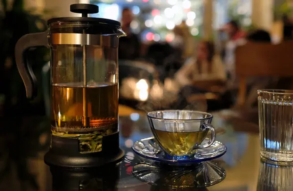 Fresh herbal tea in a transparent tea press in a cozy caf in the evening