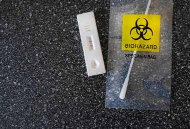 Coronavirus (COVID-19) Biyolojik tehlike içeren şeffaf bir torba içinde geniz bezinin yanında pozitif sonuç veren hızlı test 