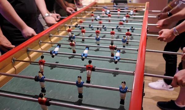 People playing at an extra-long foosball table or table football
