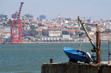 Lizbon, Portekiz limanının arka planında kargo gemileri ve şehir manzarası var.