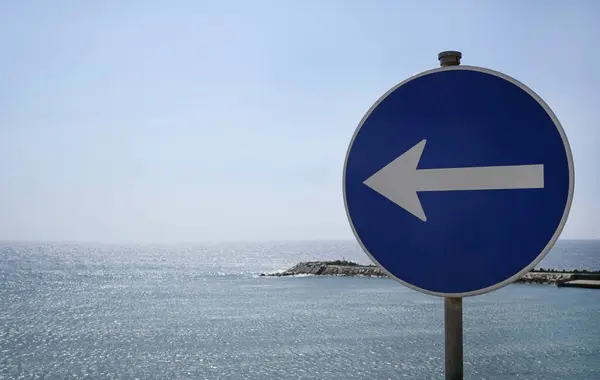 Road sign with an arrow pointing to the left at the coast of Ericeira, Portugal