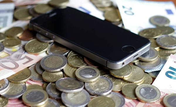 Mobile Payment and Smartphone - a mobile device lying on a pile of money