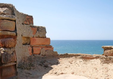 Arka planda deniz olan terk edilmiş bir binanın kırık duvarı.