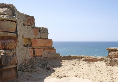 Arka planda deniz olan terk edilmiş bir binanın kırık duvarı.