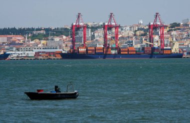 Lizbon, Portekiz - 15 Mayıs 2023: Lizbon, Portekiz limanının arka planında kargo gemileri ve şehir manzarası