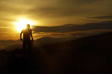 Güneş batmadan önceki son dakikalarda şapkalı bir gencin karanlık silueti..