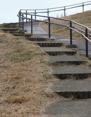 Taştan yapılmış merdivenler ve yukarıya doğru giden metal korkuluklar. 