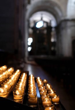 Karanlık bir kilise odasını aydınlatan bir sürü küçük mum.
