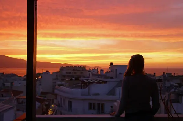 Sarışın kadın balkonda Heraklion, Girit, Yunanistan 'da günbatımının tadını çıkarıyor.