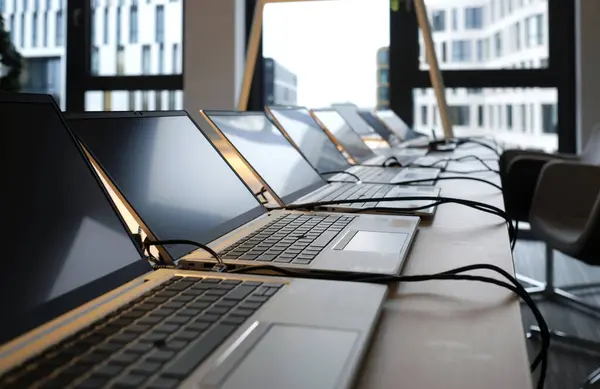 Row of laptops being prepared and set up for new employees in a company