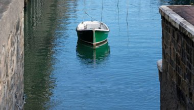 Lone green boat in the calm waters of a harbor clipart