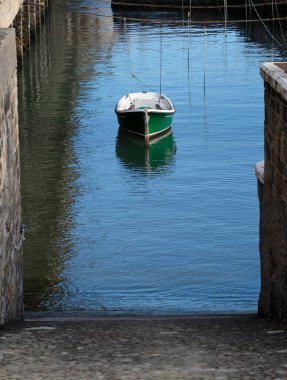 Lone green boat in the calm waters of a harbor clipart
