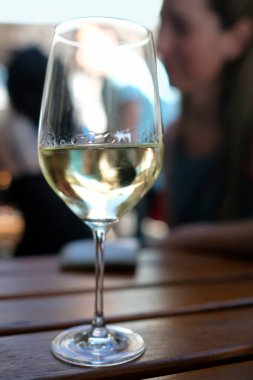 Beyaz şaraplı şarap kadehi ve arka planda bulanık bir insan.