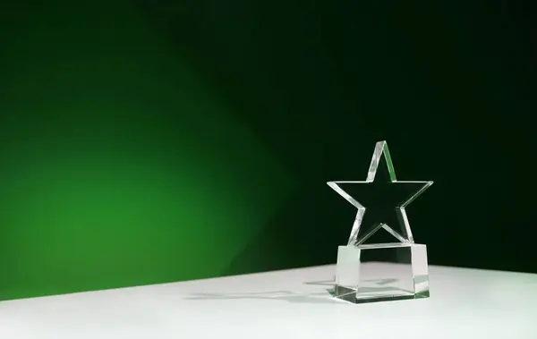 Sürdürülebilirlik ödülü - yıldız şeklinde kristal ödül yeşil spot ışıkları ve kopyalama alanı olan bir masada