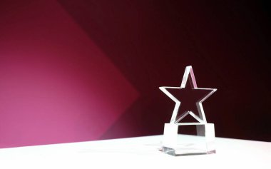 Yıldız şeklindeki kristal ödül, üzerinde pembe ışıklar ve kopyalama alanı olan bir masada.
