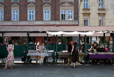 Krakow, Polonya - 5 Nisan 2025: Müşteriler malları güneşli bir günde Krakow 'da bir pazarda inceliyor