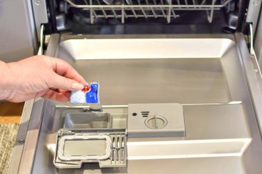 Bulaşık makinesine deterjanıyla kapsül koyan kadın.