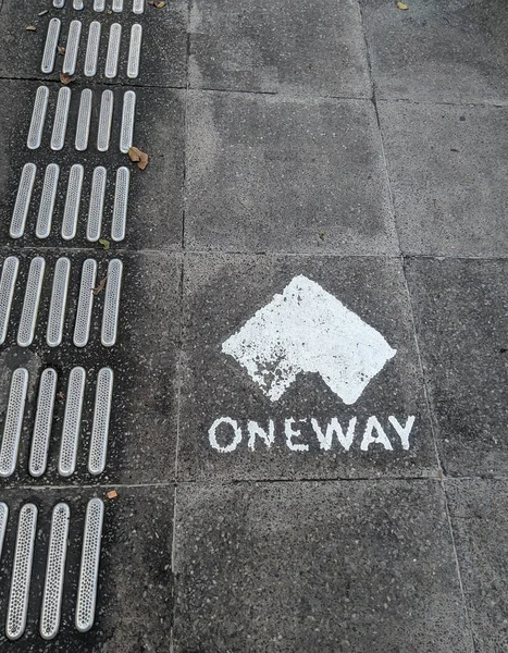 One way sign on the sidewalk. One way sign for pedestrians