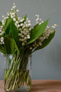 Vadinin güzel zambakları, gri ahşap arka planda yeşil ve leylak çiçekleri..