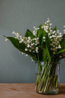 Vadinin güzel zambakları, gri ahşap arka planda yeşil ve leylak çiçekleri..