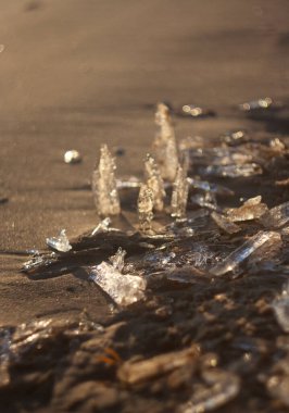 Buz kristalleri ve denizdeki kumların üzerindeki güneş..