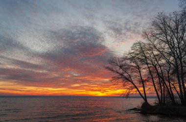 Renkli sonbahar ağaçları ve göl kıyısında gün batımı.