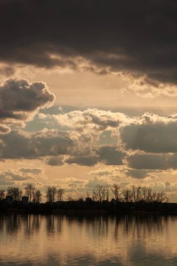 Akşamları nehirde gün batımı. Bulutlar suda yansıyor.