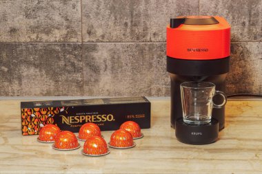 Selanik, Yunanistan - 7 Aralık 2022: Otomatik Nespresso Vertuo Pop makinesi alüminyum kapsüllerle espresso yapımında kullanıldı. Krups kahve makinesinin etrafına kahve damlatan metal balkabağı baharatları..