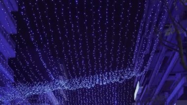 Yunanistan 'ın Selanik kentindeki süslü bir Noel LED perdesinin altında POV gecesi yürüyor.