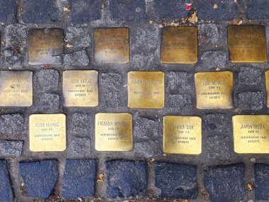 Thessaloniki, Greece - December 24 2022: Top-down street view of Jewish memorial stolpersteine outside a high school with the names of students murdered in Auschwitz in 1943. clipart