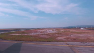 Airplane taxiing on a runway window plate POV shot on SKG Thessaloniki, Greece airport, with a city sea view.