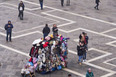 Venice Italy - February 22 2019: elevated day view of street vendor selling hats and carnival masks, with tourists on Saint Mark square, viewed from Saint Marks Basilica rooftop.