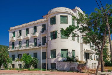 1930 'ların terk edilmiş bir oteli. Çürümüş bir cephesi ve mavi gökyüzünün altında yeşil ahşap pencereleri var..