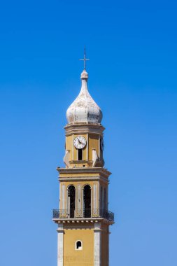 Sefalonya 'nın İyon Adası' ndaki mavi gökyüzüne karşı saati ve haçı olan renkli bir Hıristiyan kilise çan kulesi..