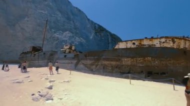 Zakynthos, Yunanistan - 10 Temmuz 2021: İyon Adaları 'nda turistlerle birlikte kumlu sahildeki ünlü çürümüş gemi enkazı ile Navagio Sahili' nin etrafında dönen Hiperlapse.