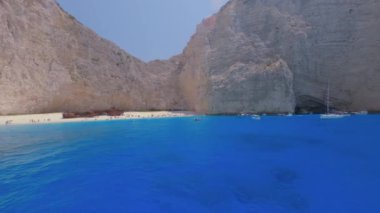 Yunanistan 'ın Zakynthos kenti, Navagio Sahili' nden denize açılırken, kumlu sahilde kimliği belirlenemeyen turistler ve İyon Adaları 'nda demirlemiş turist gemileri ile ünlü çürümüş gemi enkazı görülüyor..