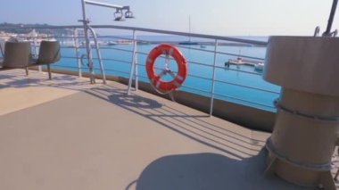 Ağır çekim POV günü, yolcu gemisinin güvertesinde, geminin demir çitlerinde asılı duran turuncu bir can simidine doğru yürüyor.. 