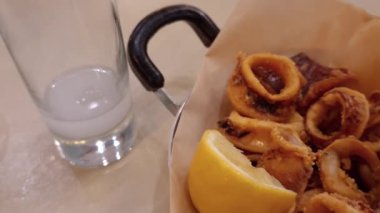 Demir tavada servis edilen kızarmış kalamar dilimleri ve bir dilim limon. Çıtır kalamar tavernası yemek konsepti.