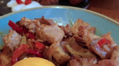 Tavuklu, domuzlu ve sosisli, kırmızı ve yeşil biberli, mantarlı ve soğanlı, dilimlenmiş limonlu, yakın görüş tavasında servis edilen et parçaları..