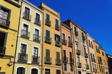 İtalya 'nın Sardunya Adası' ndaki açık mavi gökyüzü altında ahşap pencere panjurları ve demir balkonları olan Cagliari tarihi şehir merkezi renkli binalar..