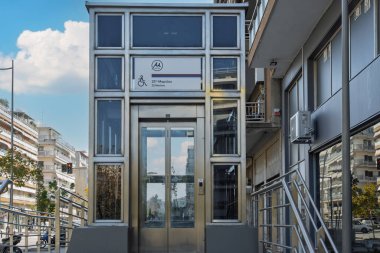 Selanik, Yunanistan - 27 Kasım 2024: yeni metro hattı 25 Martiou istasyon asansörü girişi logo ve hem Yunanca hem de İngilizce bir işaret.